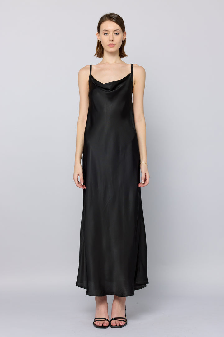 Woman wearing a black satin slip dress on a light gray background