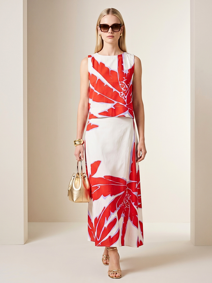 Woman wearing a red and white patterned dress with sunglasses and a handbag indoors.