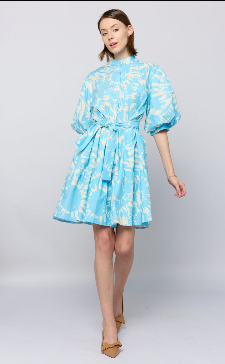 Woman wearing a light blue dress with white patterns on a plain background